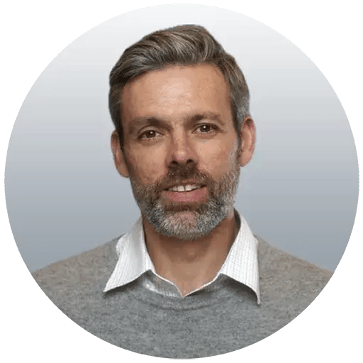 Headshot of Derek with beard and wearing a black collard shirt.