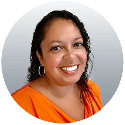 Jeannie Hale wearing an orange shirt is smiling at the camera and has black curly hair.