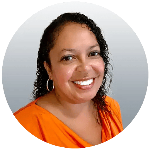 Jeannie Hale wearing an orange shirt is smiling at the camera and has black curly hair.